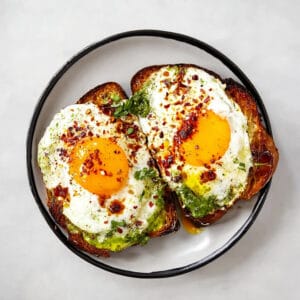 Zwei Pesto-Eier auf Sauerteigbrot mit Avocado und Käse